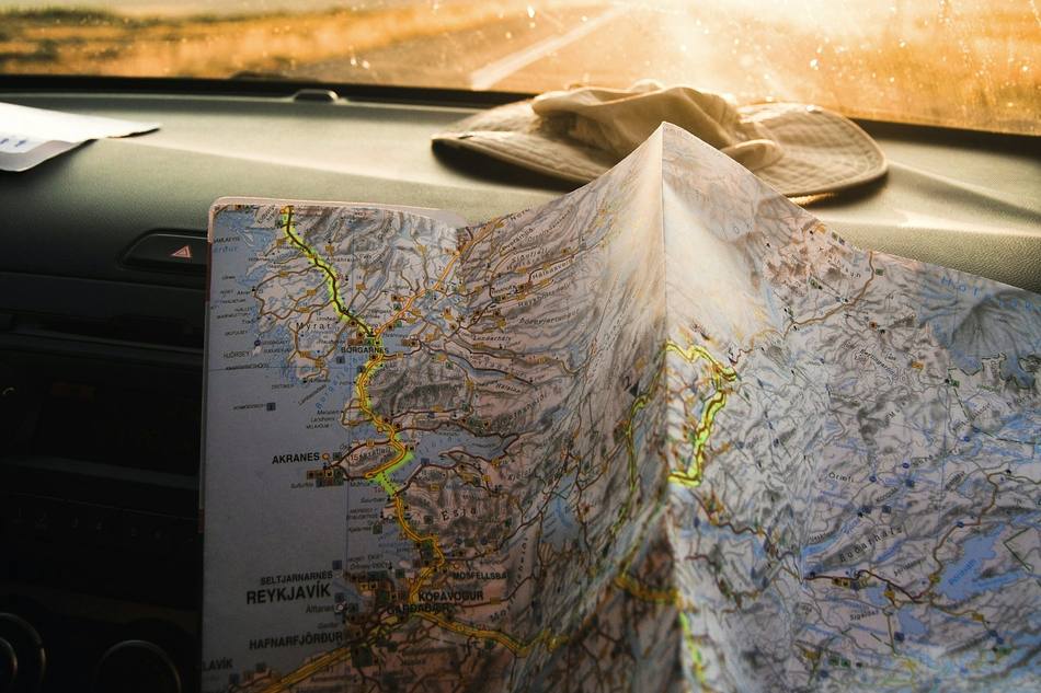 Une carte dépliée tenue à deux mains, la route se poursuit devant