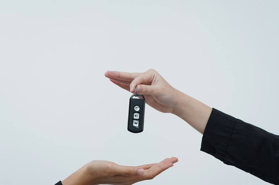 Une clé passe d'une main à l'autre, sur fond clair